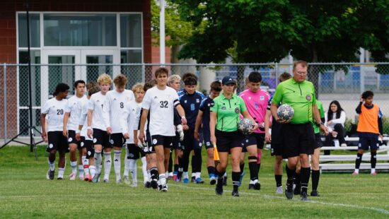Three Miners co-captains (front to back wearing white), Nicolas Janssen, Quinn Kelly walking behind number 8, and Colton Sheffield, with their heads up looking forward to the start of the game.