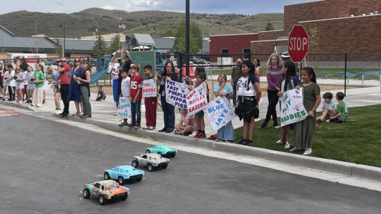 Parents and students hold hand-made signs to cheer on a heat of racers at the annual RC Club race held May 28, 2025.