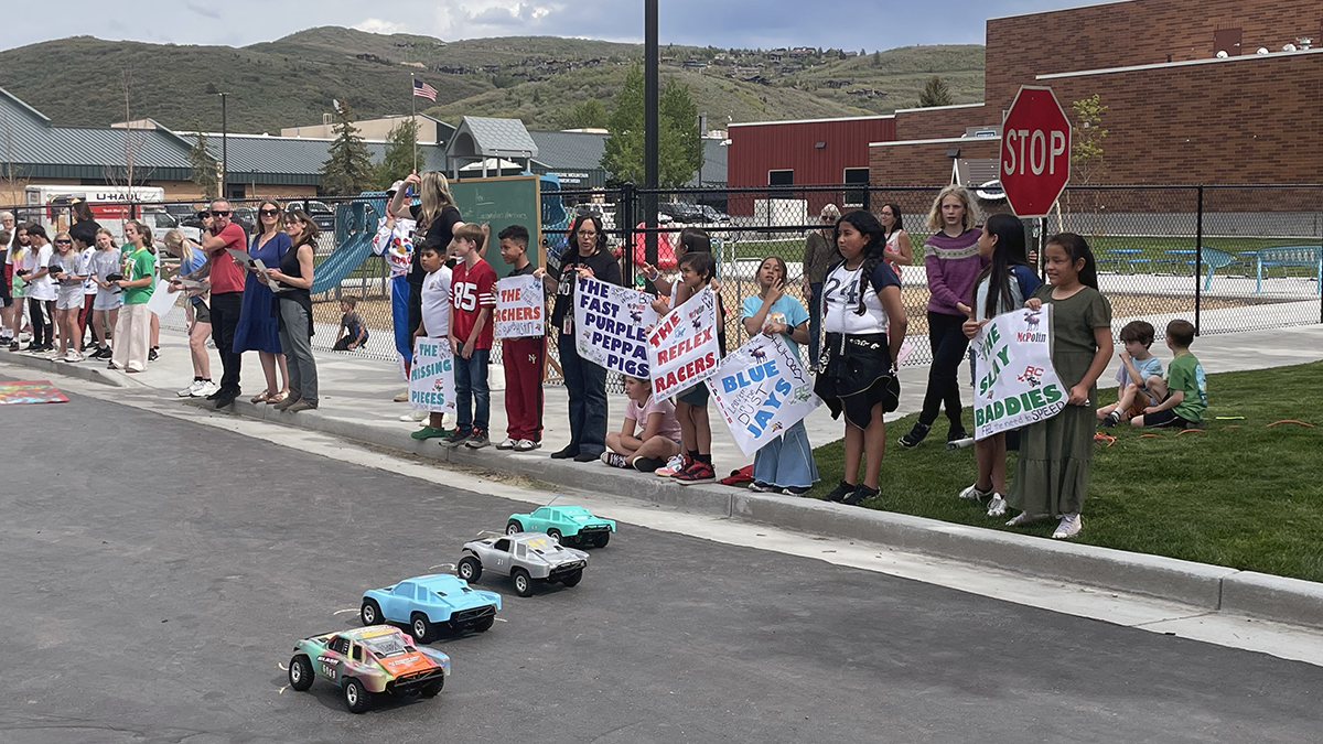 Parents and students hold hand-made signs to cheer on a heat of racers at the annual RC Club race held May 28, 2025.
