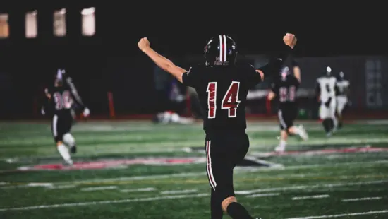 Park City senior Bash Bodily (#14) celebrates during a home game under the lights, part of a football program that has sent more than 30 players to college since 2020.