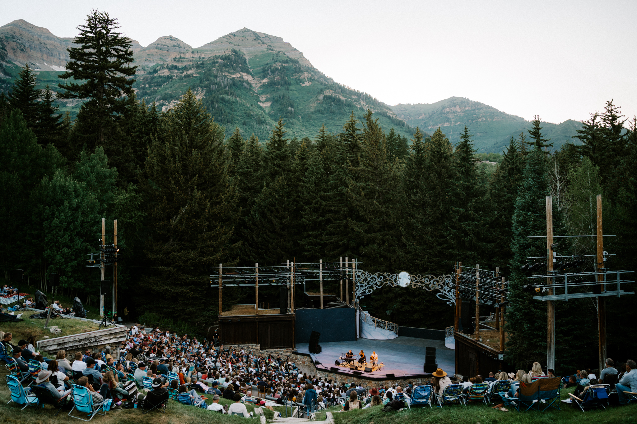 Audience members gather under the towering pines at Sundance Mountain Resort’s Outdoor Amphitheater for a Bluebird Bands performance, where live music meets the majesty of the Wasatch Range.