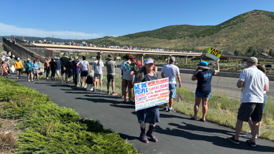 Protesters line the pedestrian overpass at Kimball Junction in Park City, Utah, on Saturday, June 14, 2025, as part of the national “No Kings” day of action.