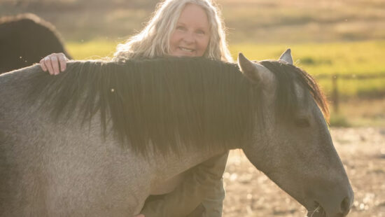 Sonya Richins, founder of Wild Heart Sanctuary, shares a quiet moment with one of the rescued mustangs on the sanctuary’s 20-acre Park City property.