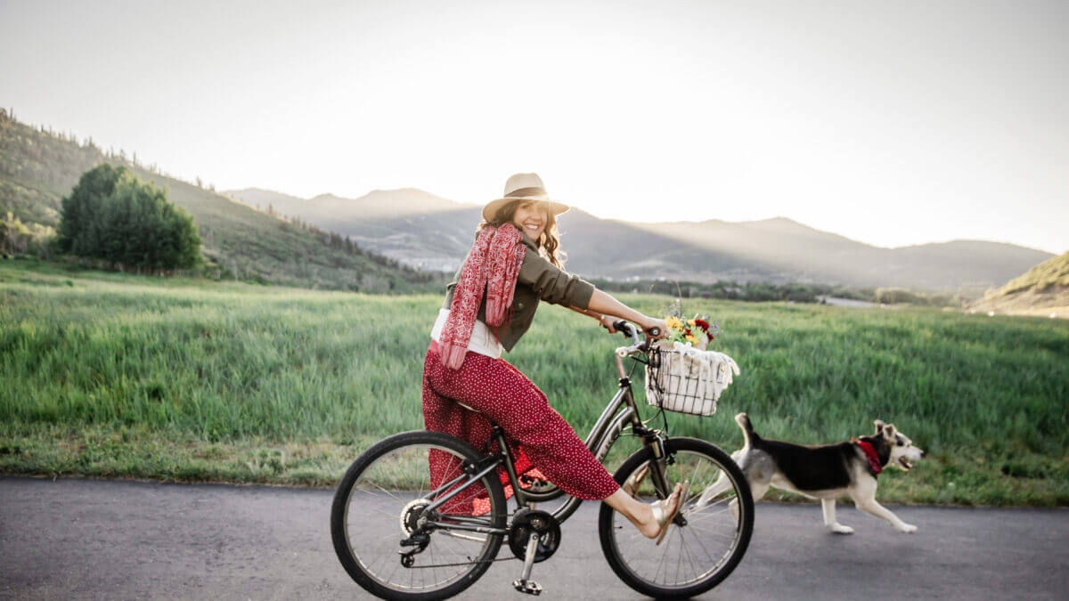 Caren Bell rides through Park City with her dog and a basket full of flowers, spreading joy ahead of the Kept Kind™ weekend campaign focused on community connection and random acts of kindness.
