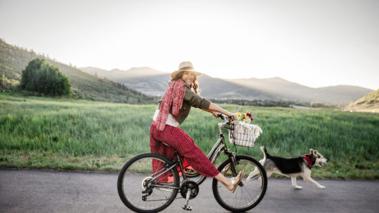Caren Bell rides through Park City with her dog and a basket full of flowers, spreading joy ahead of the Kept Kind™ weekend campaign focused on community connection and random acts of kindness.