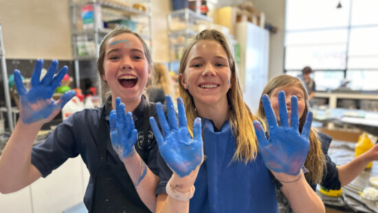 Students at Park City Day School Middle School in Park City, Utah, hold up blue paint–covered hands during an art class.