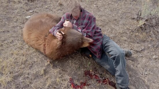 A photo of the suspect with the dead bear (suspects face is blurred).