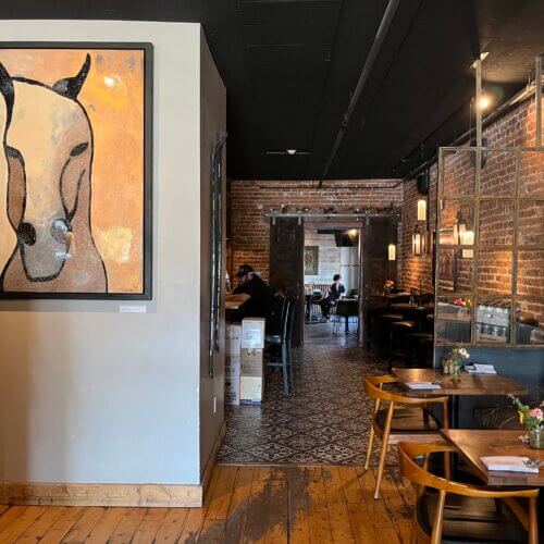 Cozy farmhouse-style dining at Midway Mercantile, where brick walls, warm lighting and art create an inviting Main Street atmosphere.