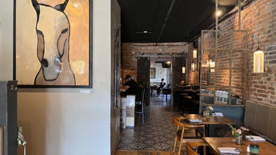 Cozy farmhouse-style dining at Midway Mercantile, where brick walls, warm lighting and art create an inviting Main Street atmosphere.