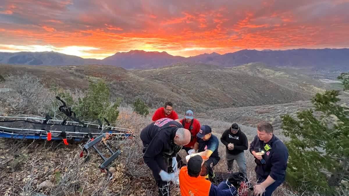 Rescuers prepare an injured hunter for evacuation as a vivid red sunset lights up the sky south of Heber City on Oct. 20, 2025. High winds forced crews to carry the patient out on foot.