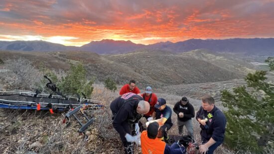 Rescuers prepare an injured hunter for evacuation as a vivid red sunset lights up the sky south of Heber City on Oct. 20, 2025. High winds forced crews to carry the patient out on foot.