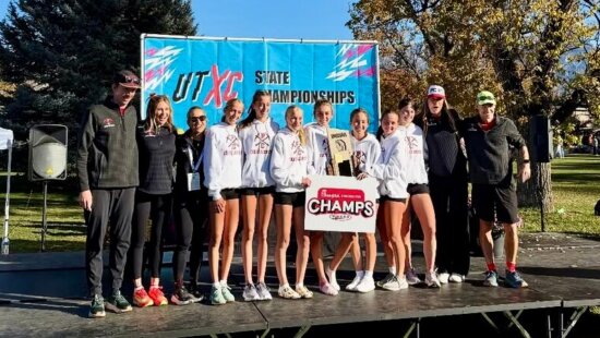 Athletes and coaches of the Park City High School Cross Country Running Team on top of the State Championships podium for their first time.