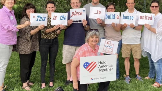 Braver Angels volunteers display signs reading "This is the place to build a house united" during a Utah organizing event. The national depolarization group launches a weeklong Mobile Summit tour Monday, offering free workshops in seven Utah cities aimed at bridging political divides.