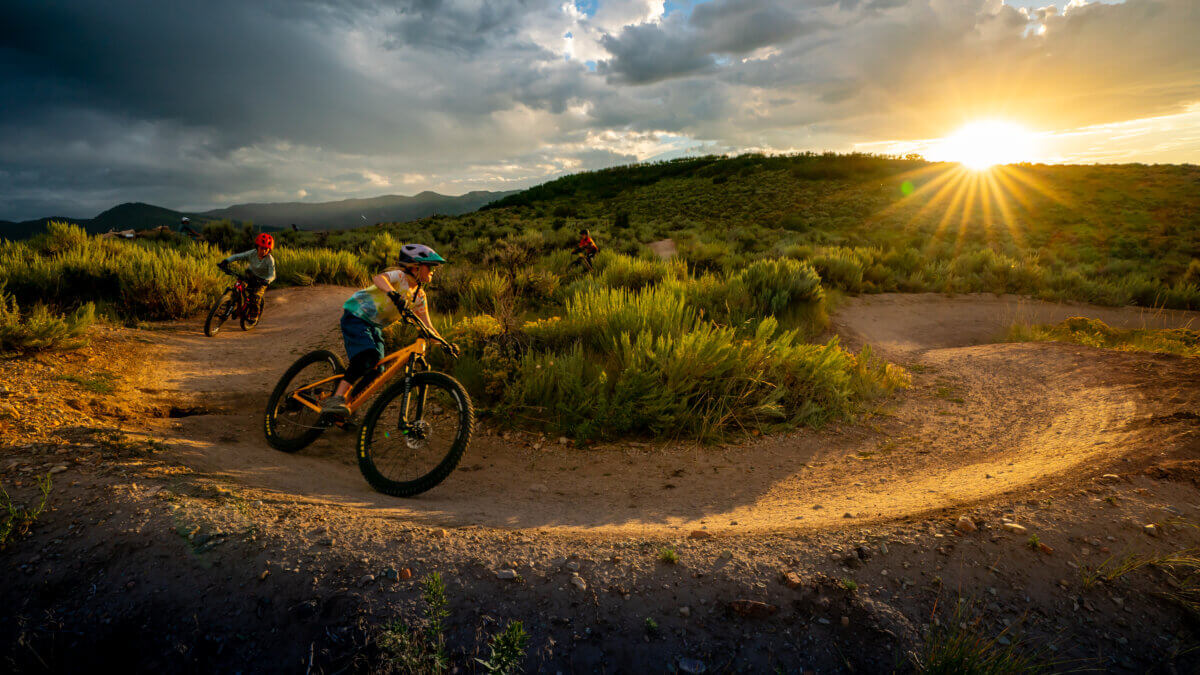 Riders carve through Park City’s singletrack at sunset, part of the 400-mile trail network whose origins local writer Linda George and filmmaker Ross Downard are documenting in a new collaborative project with the Mountain Trails Foundation.