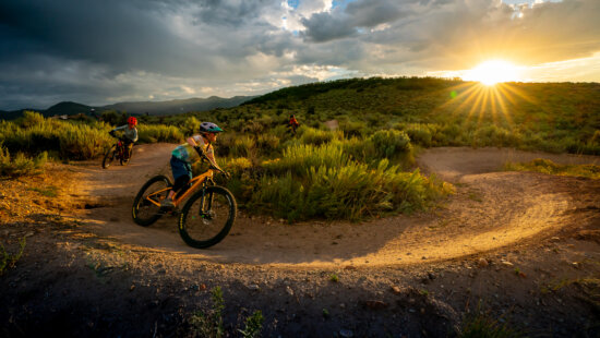 Riders carve through Park City’s singletrack at sunset, part of the 400-mile trail network whose origins local writer Linda George and filmmaker Ross Downard are documenting in a new collaborative project with the Mountain Trails Foundation.