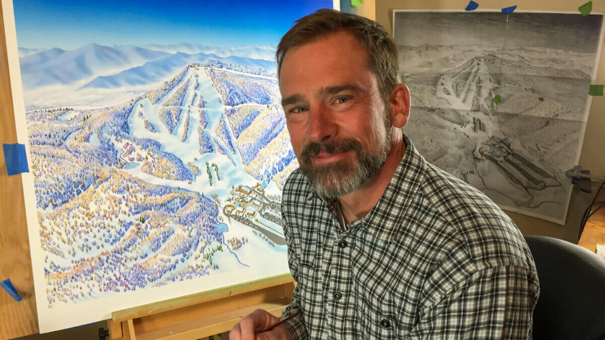 Artist Rad Smith in his Montana studio with one of his hand-painted maps. Smith, who trained under legendary ski map artist James Niehues, continues the 60-year tradition of crafting detailed, hand-rendered trail maps that blend art, geography, and mountain culture.