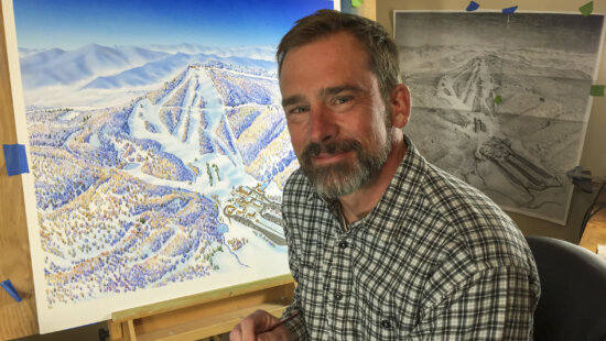 Artist Rad Smith in his Montana studio with one of his hand-painted maps. Smith, who trained under legendary ski map artist James Niehues, continues the 60-year tradition of crafting detailed, hand-rendered trail maps that blend art, geography, and mountain culture.