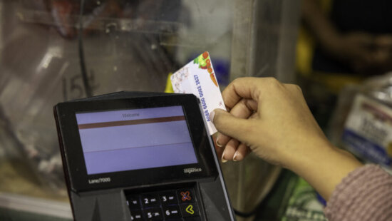 A shopper who receives SNAP benefits slides an EBT card at a checkout counter in a Washington, D.C., grocery store in December 2024.
