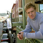 Robert Redford poses on a balcony along Main Street decorated with his Sundance Film Festival banners on Jan. 17, 2003, in Park City, Utah.