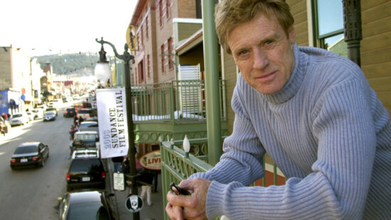 Robert Redford poses on a balcony along Main Street decorated with his Sundance Film Festival banners on Jan. 17, 2003, in Park City, Utah.