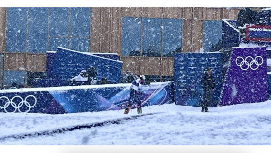 River Radamus, skis on his shoulder, exiting the Finish Area of the Milan Cortina Slalom.