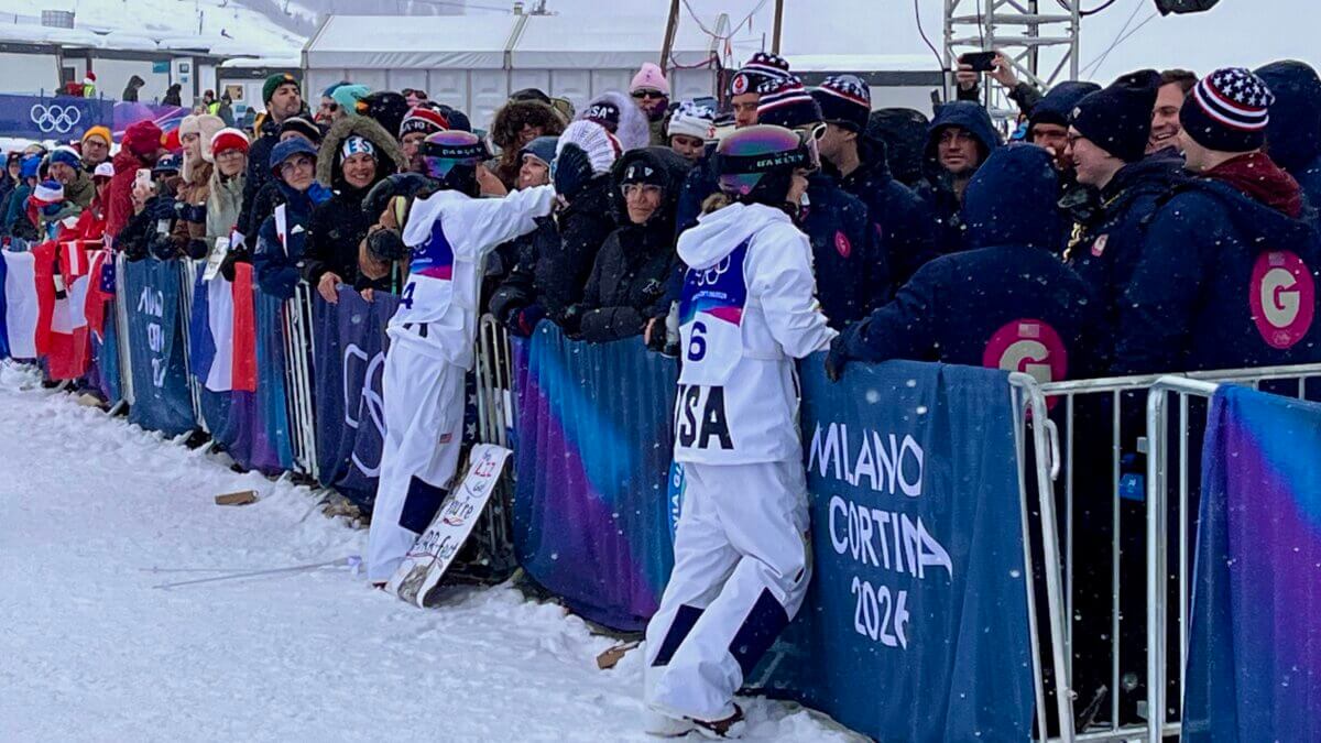 Elizabeth Lemly (L) and Olivia Giaggio, hugging their friends and family event spectators after placing top ten in the Milan Cortina Olympics for Womens Dual Moguls.