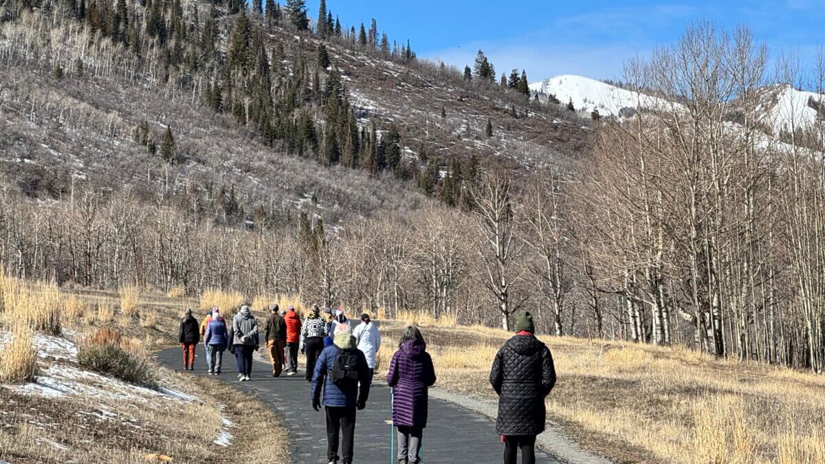 Participants walk in silence beneath blue skies and late-winter hills during a Silent Walk for Peace gathering near McPolin Barn in Park City. Organizers will continue the community walks on Saturdays, March 14, 21, and 28.