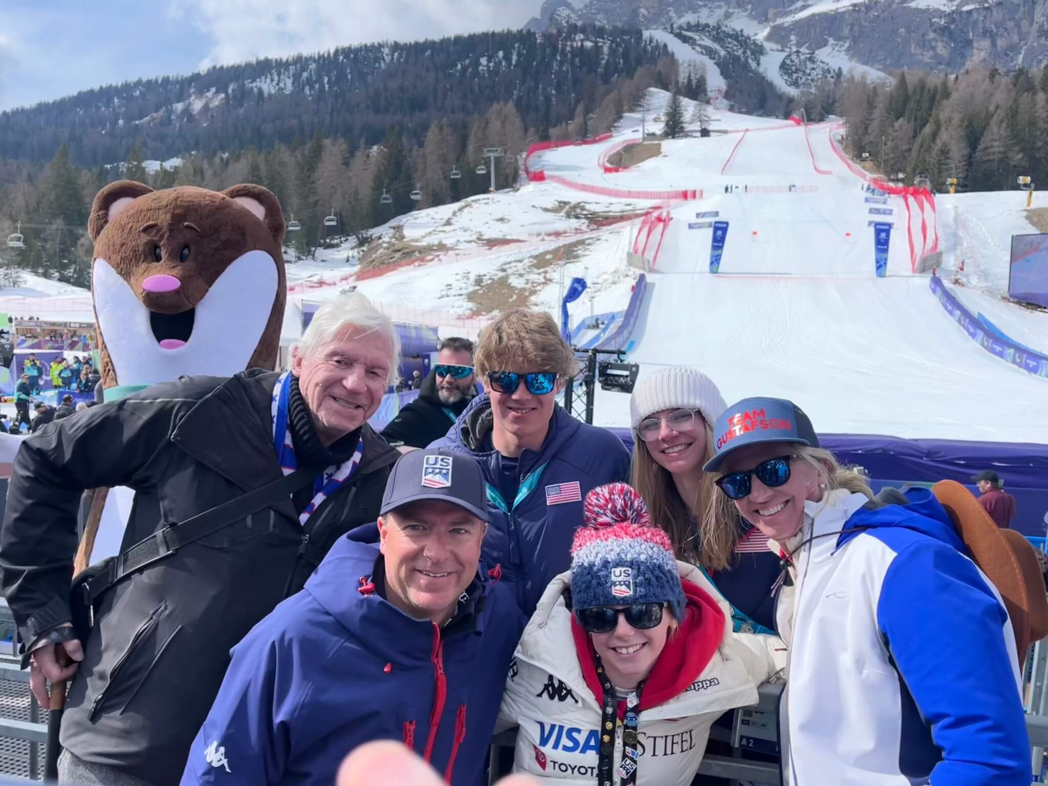 (L-R) Photo-bombing Paralympic Mascot, Tina, Grandpa Gustafson, Dad Gustafson, Spenser, little sister, Hope, Meg, and Mama Gustafson in Milan Cortina.