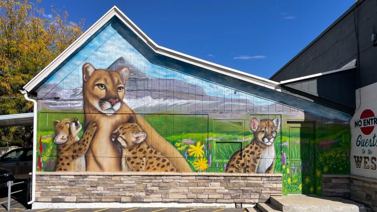 Anna Nizhoni’s mural features a mountain lion and cubs against a mountain landscape, blending wildlife, public art and a sense of place.