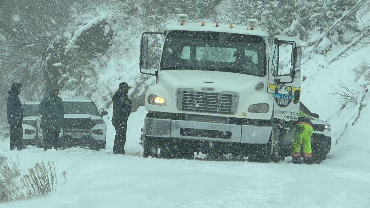 Near-whiteout conditions made for difficult footing as crews worked to clear the disabled tow truck and damaged Jeep from the road.