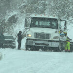Near-whiteout conditions made for difficult footing as crews worked to clear the disabled tow truck and damaged Jeep from the road.