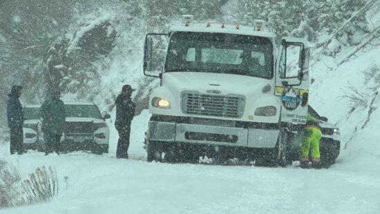 Near-whiteout conditions made for difficult footing as crews worked to clear the disabled tow truck and damaged Jeep from the road.
