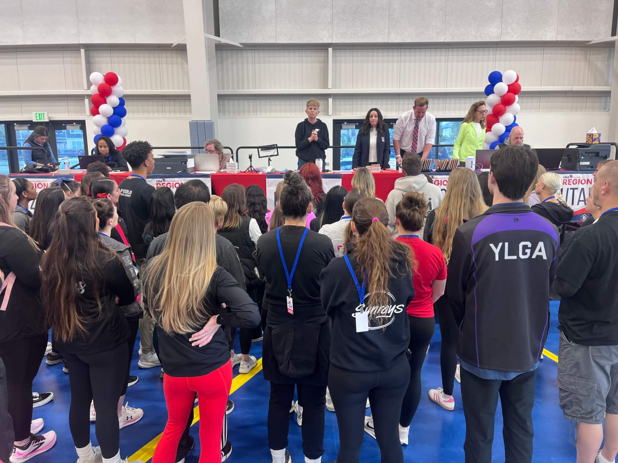 Katy Heddens (on stage, short. blonde, hair) leading the USA Gymnastics-sanctioned event.