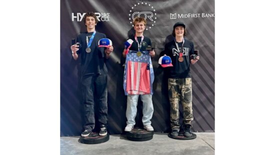 Samuel McKenzie, center, stands atop the podium after winning the Amateur 14-18 division at the 2026 USA Cycling BMX Freestyle National Championships at COR Park in South Jordan.