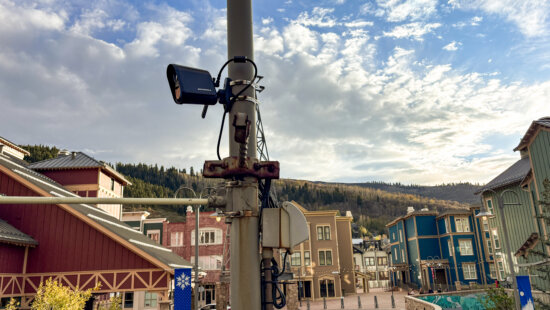 A Motorola license plate reader mounted on a pole near the corner of State Route 224 and Main Street in Park City, with Old Town in the background.