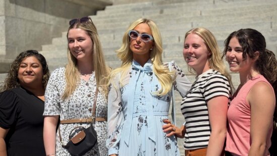Paris Hilton, center, poses for a group photo after a news conference in Provo on June 15, 2026.