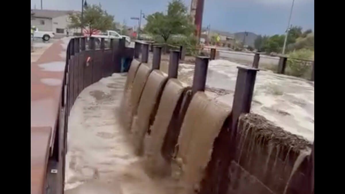 Muddy floodwater pours over the edge of the bike path underpass along the Poison Creek Trail on Friday, July 17, as heavy monsoon rains swelled the creek beyond its banks