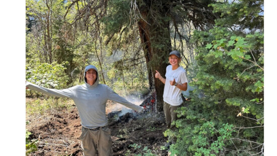 Utah Conservation Corps members Adeline Bondurant, right, and Ethan Fergen, left, stand beside the lightning-struck tree she helped locate at the 910 Ranch on July 21. Park City Fire District crews extinguished the fire before it spread beyond the tree.