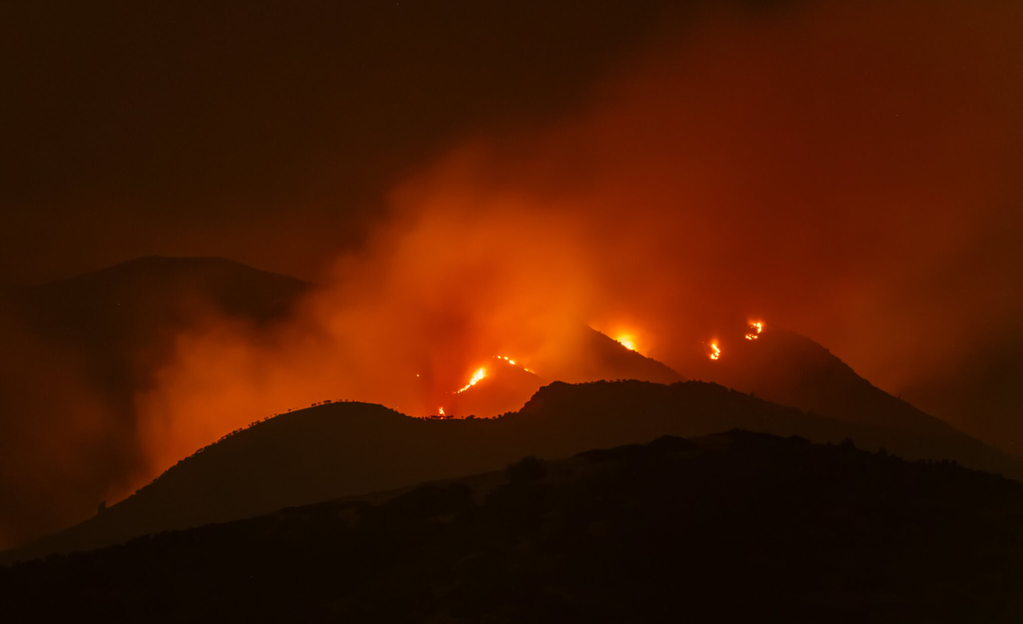 Flames from the Rocky Canyon Fire glow along ridgelines as seen from Pinebrook on Saturday night, Aug. 8, 2026. The fire burned actively until approximately 2 a.m. Sunday, growing to more than 2,800 acres.