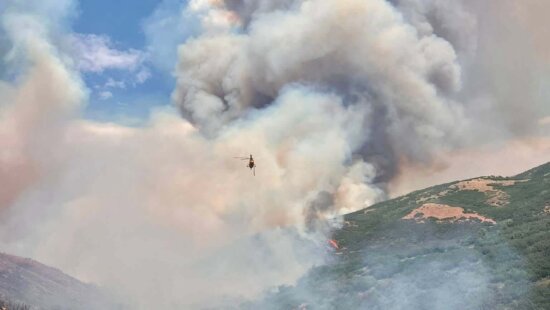 A helicopter conducts water bucket operations over the Rocky Canyon Fire on Saturday, Aug. 8, 2026. The fire grew to an estimated 2,800 acres overnight with 0% containment, and crews are using aviation resources along with dozers and hand crews to secure the fire perimeter.