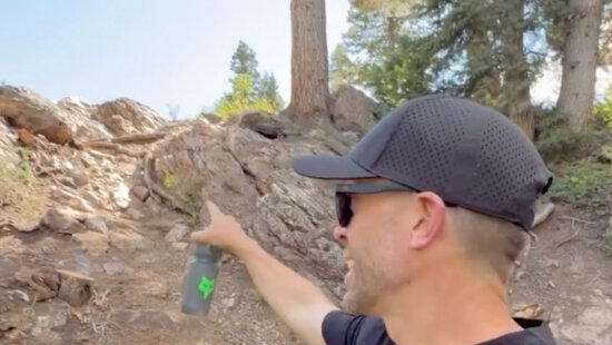 US Open co-founder Clay Harper points out Niagara, a rock section preserved from the original early-2000s NCS track. The classic feature now flows into a rebuilt exit with a larger, faster berm