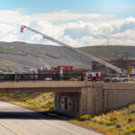 Park City Fire District crews fly an American flag from a ladder truck over Interstate 80 ahead of the procession bringing fallen helicopter pilot Ryan Cutter home to Summit Park on Tuesday, Sept. 29, 2026.